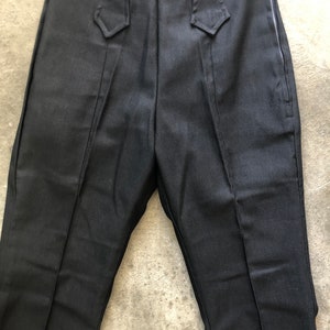 May include: Black pants with a side zipper and decorative waist details. The pants have a label that reads "Panhandle Slim". The pants are made of a dark fabric.
