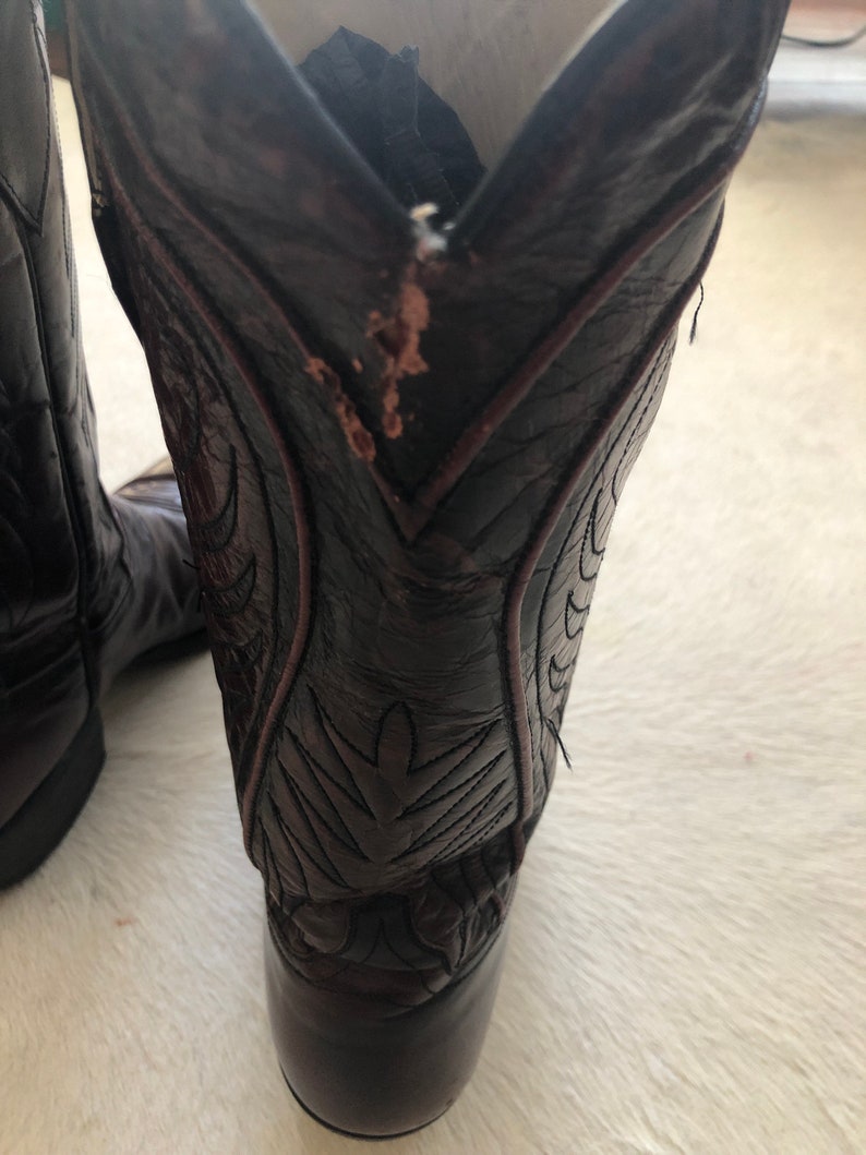 Puede incluir: Botas de vaquero de cuero marr&oacute;n oscuro con costuras decorativas. Las botas tienen una puntera puntiaguda y un tac&oacute;n apilado. El cuero muestra algo de desgaste. Las botas est&aacute;n dise&ntilde;adas para montar a caballo y trabajar.