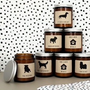 May include: A set of seven amber glass candles with brown paper labels and black dog and cat silhouettes. The labels have humorous sayings about dogs and cats, such as "It's been a long day!" and "Pugs need hugs".