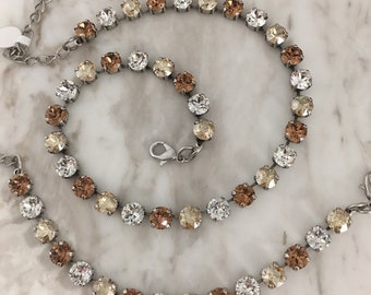 May include: A silver chain necklace and bracelet with a multi-colored crystal design. The crystals are clear, light brown, and dark brown.