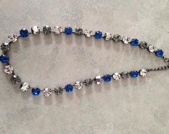 May include: A silver chain necklace with blue, clear, and gray crystal beads.