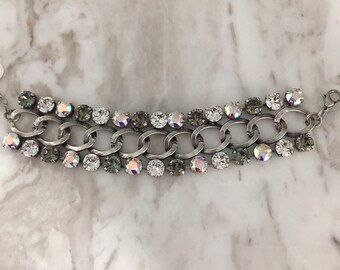 May include: A silver chain bracelet with clear and iridescent crystals. The bracelet has a double row of crystals.