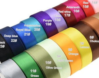 May include: A collection of 23 different colored satin ribbon spools. The spools are arranged in a semi-circle, with the colors ranging from black to white. Each spool has a number and color name printed on it.