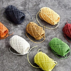 May include: Assortment of eight spools of colorful twine, each wound into a ball shape. The colors include orange, yellow, green, red, white, brown, and blue.