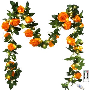 May include: A string of orange artificial rose flower lights with green leaves. The lights are strung on a copper wire and are powered by a USB plug. The lights are controlled by a remote control.