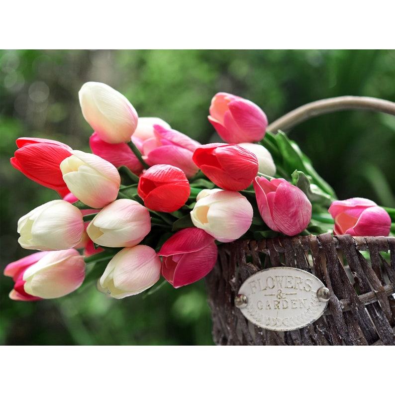 May include: A bouquet of pink and white tulips in a brown wicker basket with a white sign that reads "Flowers & Gardens".