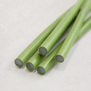 May include: A collection of four cylindrical rods featuring a smooth, matte olive green exterior coating and a light gray, circular core visible at the ends. The rods are arranged in a parallel, slightly overlapping cluster, showcasing their uniform shape.