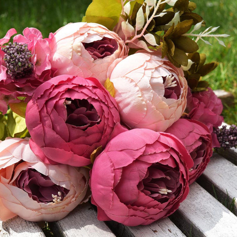 Puede incluir: Un ramo de peon&iacute;as artificiales de color rosa y burdeos con hojas verdes.