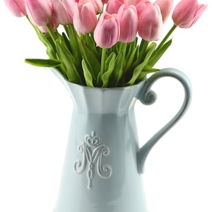 K&ouml;nnte beinhalten: Ein Strau&szlig; k&uuml;nstlicher rosa Tulpen in einem hellblauen Keramik Krug mit einem dekorativen silbernen Kronen- und Buchstaben M-Design. REFERENZFOTO MIT 20 ST&Uuml;CK