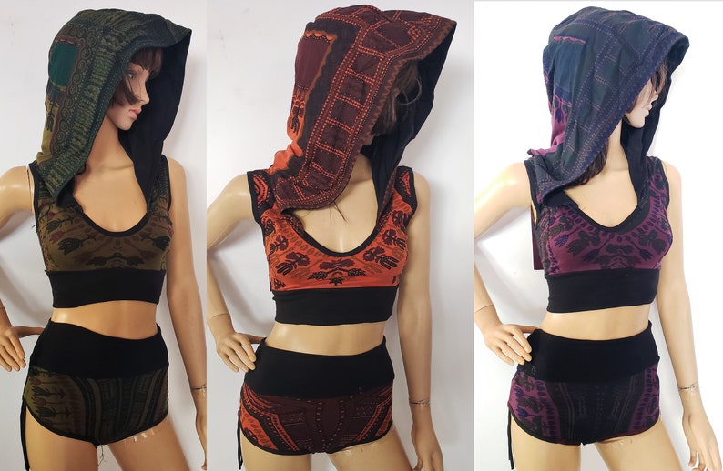 Puede incluir: Tres tops sin mangas con pantalones cortos a juego en diferentes combinaciones de colores. Los tops tienen un escote con capucha y una banda negra en la parte inferior. Los pantalones cortos tienen una cintura negra y cordones de ajuste en los lados. Los colores son verde, naranja y morado.