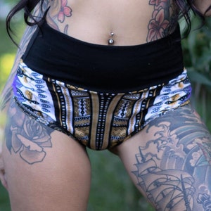 Puede incluir: Pantalones cortos de cintura alta con estampado blanco y negro y cintura negra. Los pantalones cortos tienen un dise&ntilde;o geom&eacute;trico con detalles dorados. La modelo lleva los pantalones cortos con un top corto negro.