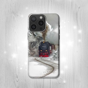 May include: A black and red steam locomotive train engine with smoke coming from the chimney, traveling through a snowy winter landscape. The train is on a track with a curved path. The background is a snowy forest with a cloudy sky.