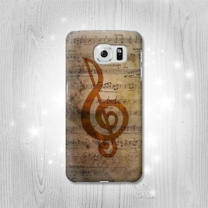 Puede incluir: Una funda para teléfono con un fondo de partitura musical vintage y una gran clave de sol naranja en el centro.
