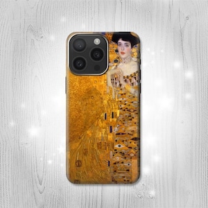 May include: A gold iPhone case with a painting of a woman in a gold dress. The painting is a reproduction of Gustav Klimt's "The Kiss".