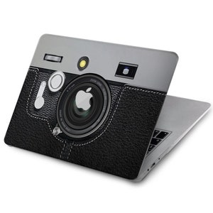 May include: A silver and black laptop case with a vintage camera design. The case features a faux leather texture and a silver lens with the Apple logo in the centre.
