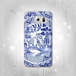 May include: Blue and white phone case featuring a traditional Chinese design. The design includes a willow tree, a bridge, a pagoda, and birds.