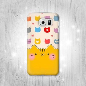 May include: A yellow phone case with a cartoon cat design. The cat has a pink nose and cheeks. The background is cream with colorful cat silhouettes and hearts.