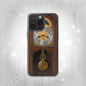 Puede incluir: Una funda de teléfono de madera marrón con una esfera de reloj de color dorado y un péndulo. La esfera del reloj tiene números romanos y un diseño decorativo. La funda tiene una lente de cámara negra con tres lentes.