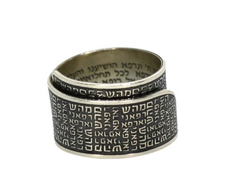 May include: A silver ring with Hebrew text engraved on the band. The ring is designed to be worn on the finger with the text facing inward.