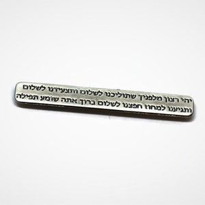 May include: A silver metal bar with Hebrew text engraved on it. The text reads: "יהי רצון מלפניך שתוליכנו לשלום ותצעידנו לשלום ותגיענו למחוז חפצנו לשלום ברוך אתה שומע תפילה"