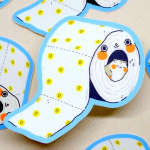May include: A set of colourful stickers featuring a cartoon hamster sleeping inside a toilet roll. The toilet roll is white with yellow dots and a blue border. The hamster is white with orange cheeks and is sleeping with its eyes closed. The stickers are perfect for adding a touch of whimsy to any surface.