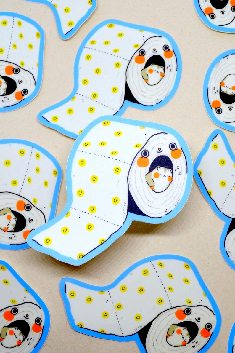May include: A set of colourful stickers featuring a cartoon hamster sleeping inside a toilet roll. The toilet roll is white with yellow dots and a blue border. The hamster is white with orange cheeks and is sleeping with its eyes closed. The stickers are perfect for adding a touch of whimsy to any surface.