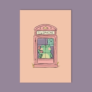 Puede incluir: Una ilustración caprichosa presenta una cabina telefónica rosa con la palabra «TELEPHONE» en la parte superior. Dentro, una rana verde está usando el teléfono alegremente. El fondo es de color melocotón suave, con un borde púrpura.