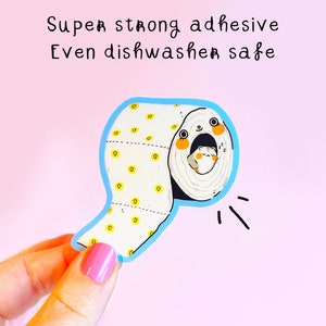 May include: A blue and white sticker of a toilet paper roll with a hamster peeking out. The sticker has yellow dots and the text "Super strong adhesive Even dishwasher safe".