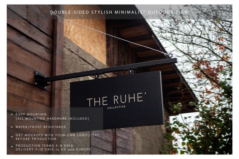 May include: A black, double-sided outdoor sign with the text "THE RUHE' COLLECTIVE" in gold lettering. The sign is suspended from a black metal bracket and cable. The sign is mounted on a wooden building.