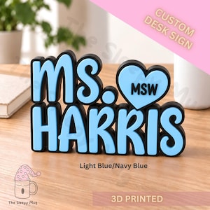 May include: A 3D printed custom desk sign featuring the text MS. HARRIS in light blue letters with a black outline. A light blue heart shape with the black text MSW is positioned to the right of the letters. The sign is light blue and navy blue.