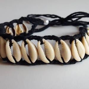 May include: A black cord bracelet with white cowrie shells. The bracelet has a tie closure.