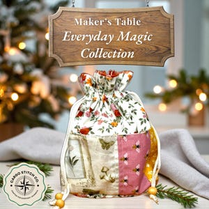 Puede incluir: Una bolsa con cordón de la "Everyday Magic Collection" con una parte superior floral y un diseño de patchwork. El patchwork incluye mariposas, abejas e ilustraciones botánicas. La bolsa es blanca, rosa y amarilla con un letrero de madera que dice "Maker's Table" y "Everyday Magic Collection".