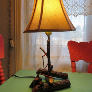 Handcrafted wrought iron lamp with saw and axes on log, country, rustic.
