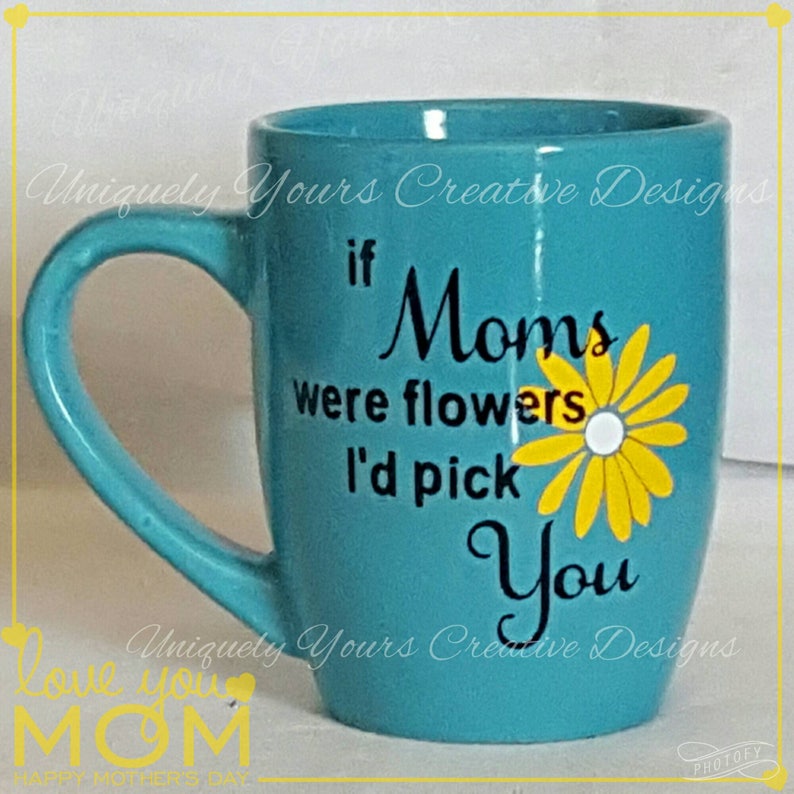 May include: A turquoise ceramic mug with a black and yellow design. The mug has a handle and says "If Moms were flowers I'd pick you".