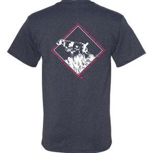 May include: A dark heather grey t-shirt with a white graphic of a dog pointing and the text "Hunt, Point, Shoot, Retrieve" repeated around the dog in a diamond shape. The text is in pink.