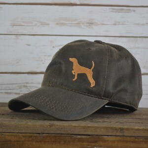 Może przedstawiać: Ciemnobrązowa, pł&oacute;cienna czapka z daszkiem z haftowanym brązowym siluetem psa z przodu.