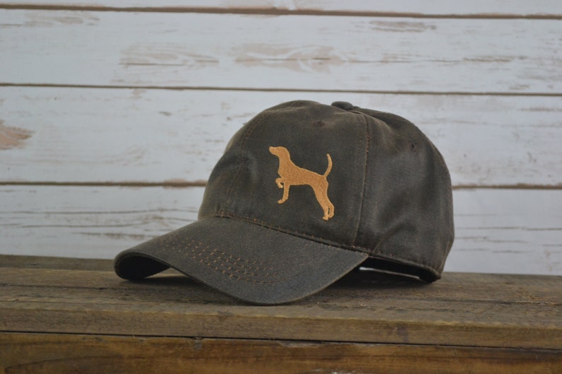 Może przedstawiać: Ciemnobrązowa, pł&oacute;cienna czapka z daszkiem z haftowanym brązowym siluetem psa z przodu.