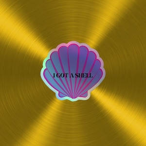 Könnte beinhalten: Ein holografischer Aufkleber mit einer lila Muschel und dem Text "I GOT A SHELL" auf goldenem Hintergrund.