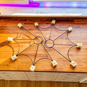 May include: Two black metal fire poi with eight white wick tips. The poi are laid out on a wooden surface.