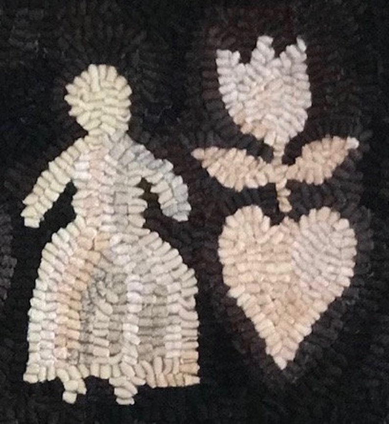 May include: A handmade rug with a black background features a white figure of a person, a tulip, and a heart. The figures are made of small, textured pieces, creating a unique, folk art style. The rug is likely made of wool or a similar material.