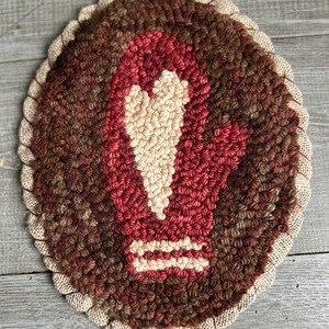 Peut inclure: Un tapis en laine fait main avec un motif de flèche stylisé au centre. Le tapis est de couleur marron, rouge et crème.