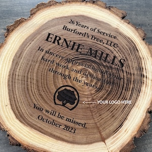May include: A wooden plaque with a tree ring design, engraved with the text "26 Years of Service Burford's Tree, LLC ERNIE MILLS In sincere appreciation of your hard work and dedication through the years. You will be missed. October 2023."