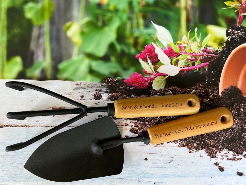 May include: A set of two gardening tools with wooden handles. The handles are engraved with the text "Sean & Rhonda - June 2024" and "We hope you DIG retirement".