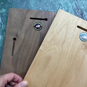 May include: Two wooden plaques, one dark brown and one light brown, with keyhole slots for hanging. Each plaque has a circular sticker with an American flag and the text "PREMIUM WALNUT MADE IN U.S.A."