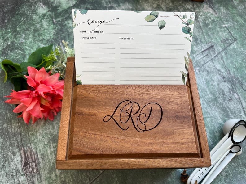 Pu&ograve; includere: Scatola per ricette in legno con un monogramma personalizzato "LRD" sul davanti. La scatola ha uno slot per le schede delle ricette con un design floreale e le parole "ricetta", "da casa di", "ingredienti" e "istruzioni".
