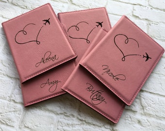 May include: Four pink passport holders with a heart and airplane design. The holders are personalized with the names Aleena, Amy, Nicole, and Brittany.