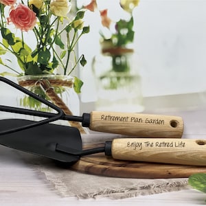 May include: A set of two gardening tools with wooden handles. The handles are engraved with the text "Retirement Plan: Garden" and "Enjoy The Retired Life".