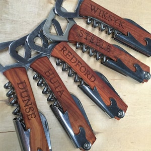May include: Five wooden bottle openers with corkscrews. Each opener has a different name engraved on it: Wiksy, Steele, Redford, Huita, and Dunse.