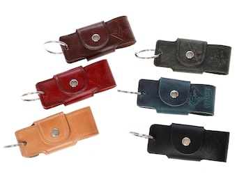May include: Six leather keyrings in different colours, including brown, red, tan, green, blue, and black. Each keyring has a metal ring and a snap closure.