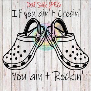Może przedstawiać: Czarno-biały projekt graficzny przedstawiający dwa buty Crocs z tekstem "If you ain't Crocin' you ain't Rockin'" na białym drewnianym tle.